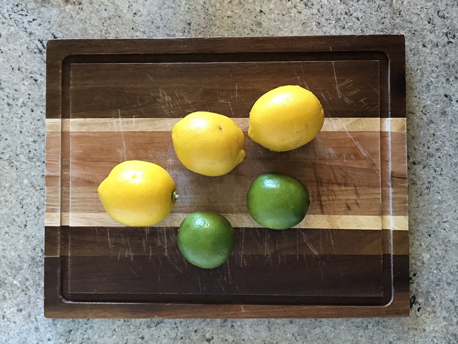 Whole lemons and limes on a cutting board